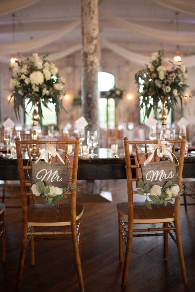 Bride and groom’s Chiavari chairs with floral accents and custom signage at Hilton Head wedding reception.