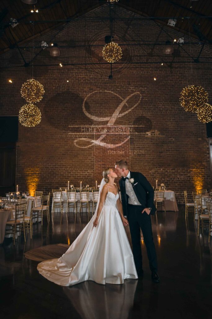 Romantic detail of bride and groom holding hands during a reception reveal under string lights.
