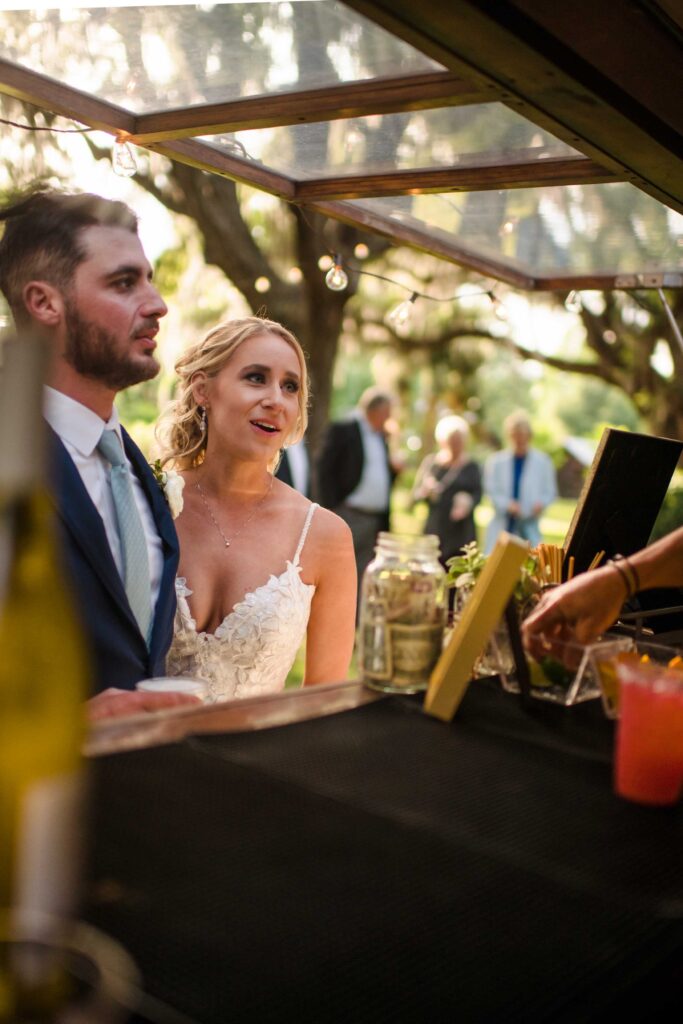 Bride and groom ordering drinks at a vintage trailer bar during a South Carolina wedding reception.
