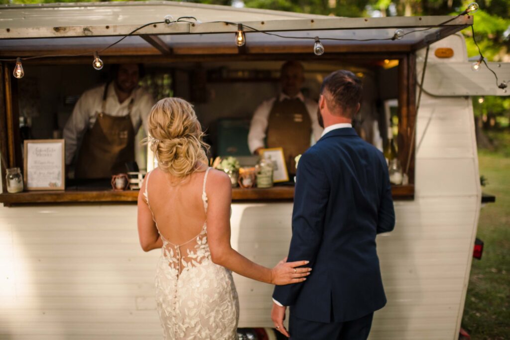 Bride and groom ordering drinks at a vintage trailer bar during a South Carolina wedding reception.