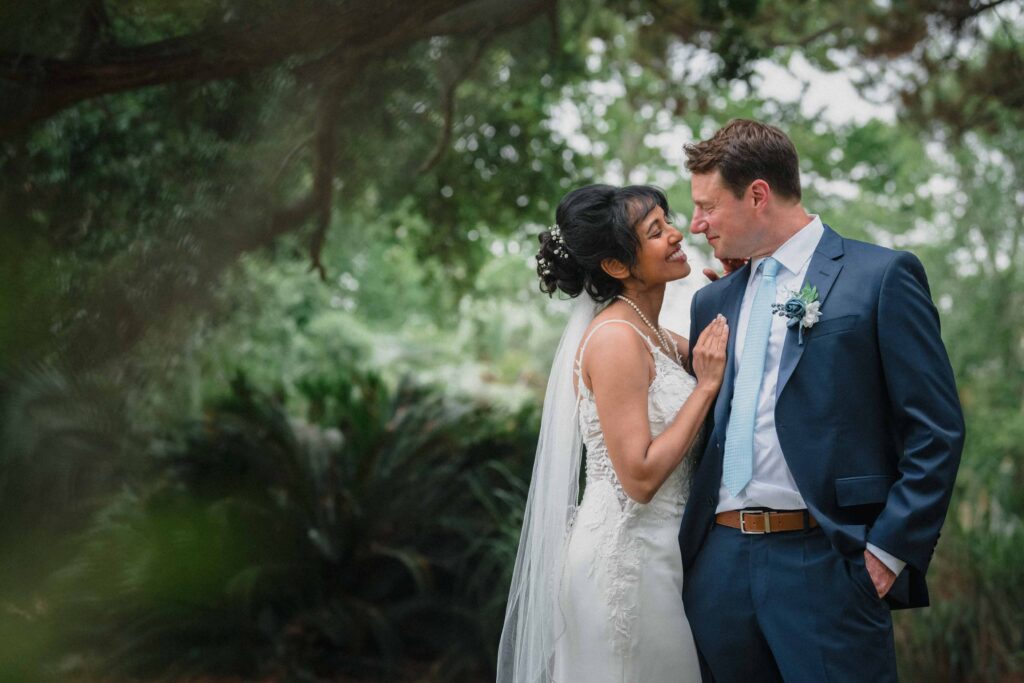 Bride draped on groom’s shoulder during romantic wedding portrait in Savannah GA.