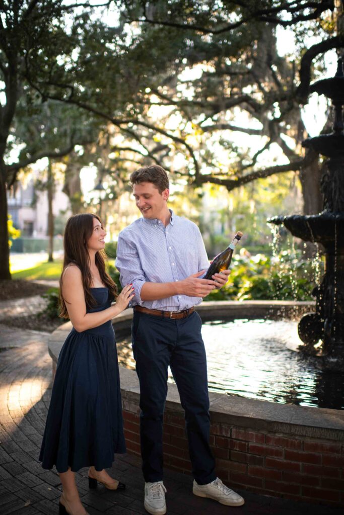 Couple popping champagne near fountain at Lafayette Square in Savannah GA.