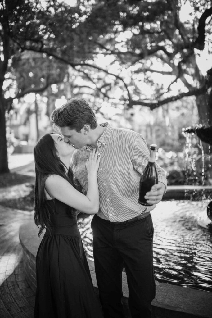 Couple popping champagne near fountain at Lafayette Square in Savannah GA.
