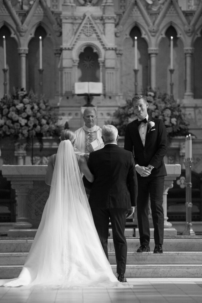 groom smiling at his bride seeing her  walk down the isle at Cathedral Basilica Savannah Georgia